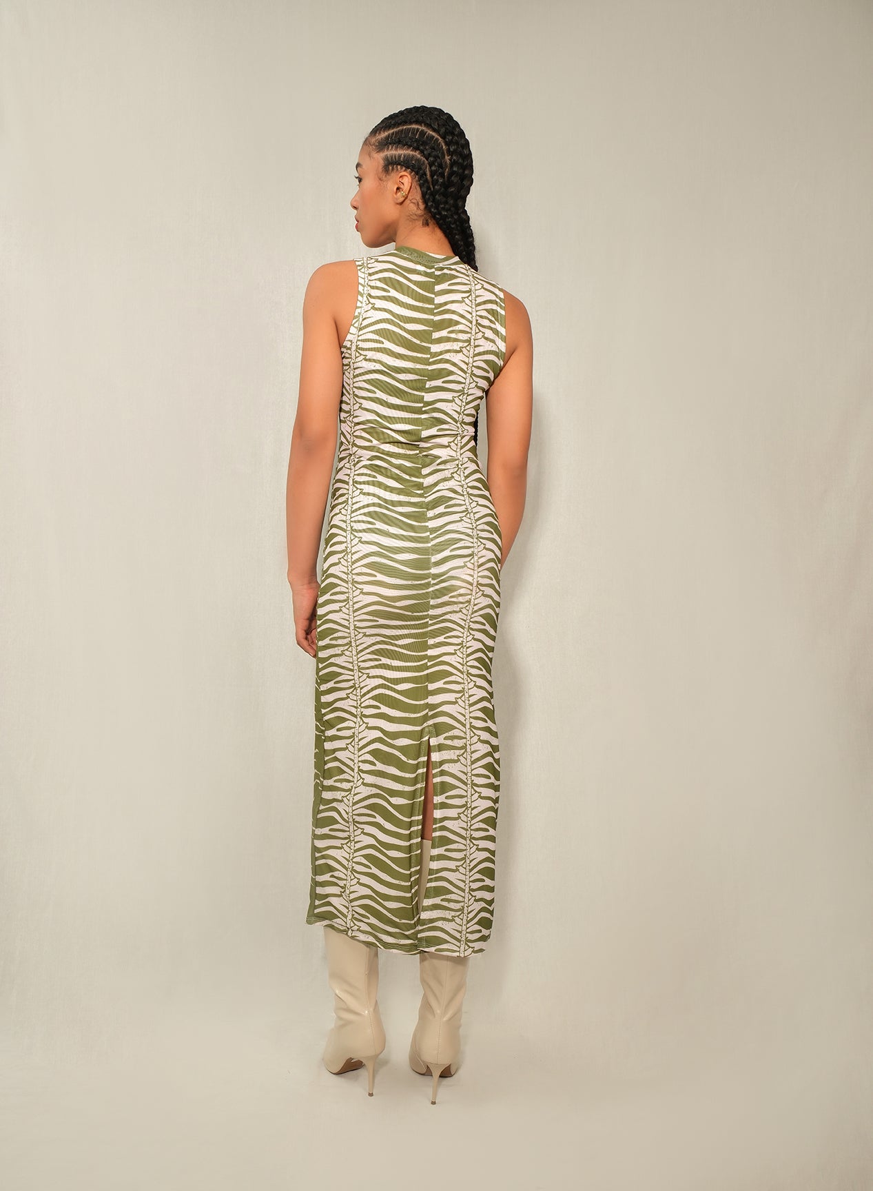 Model wearing sleeveless mesh column midi dress in Green Snake print with back slit.