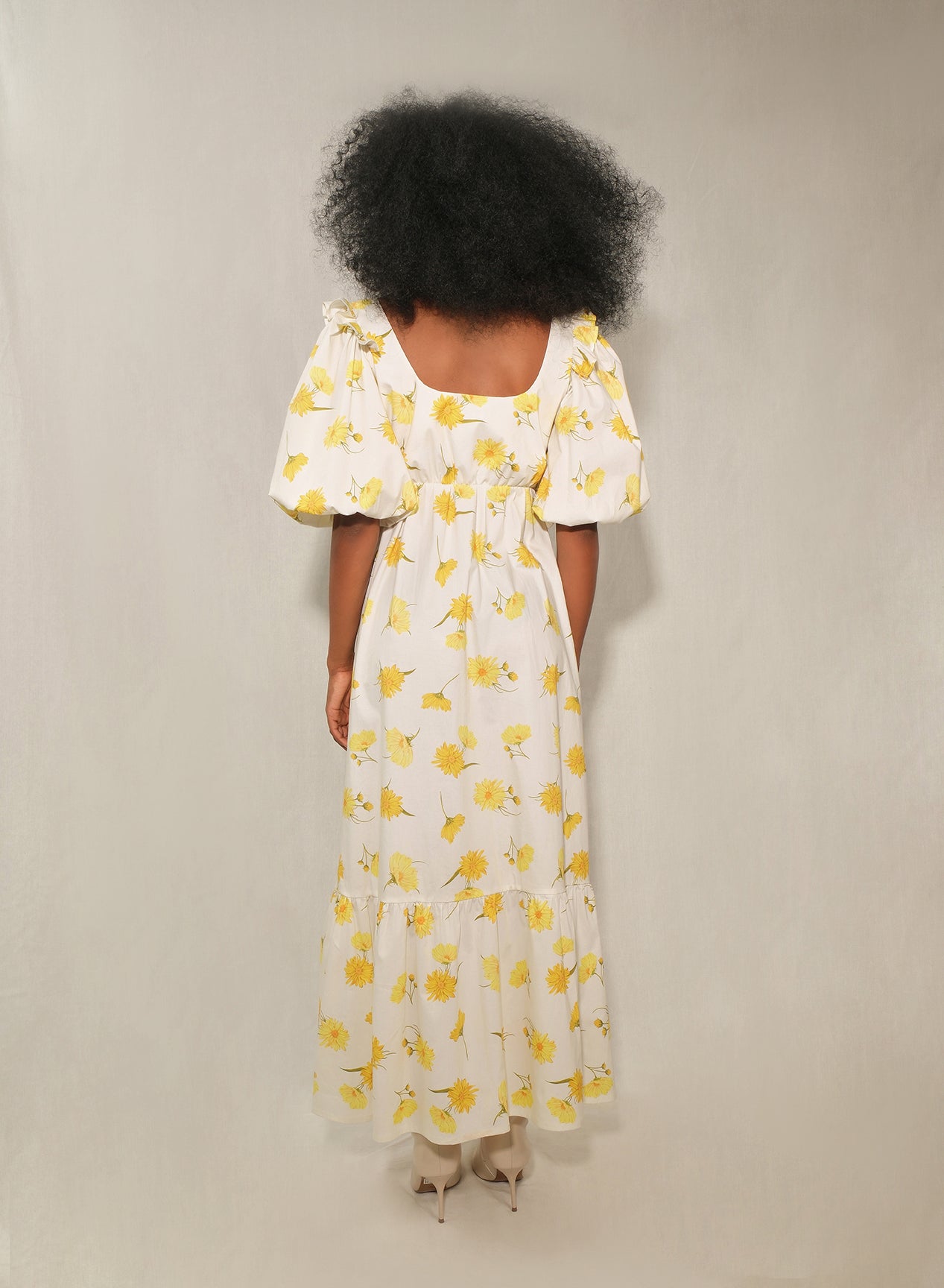Model in floral puff-sleeve bow-front maxi dress with tiered skirt in yellow daisy print.