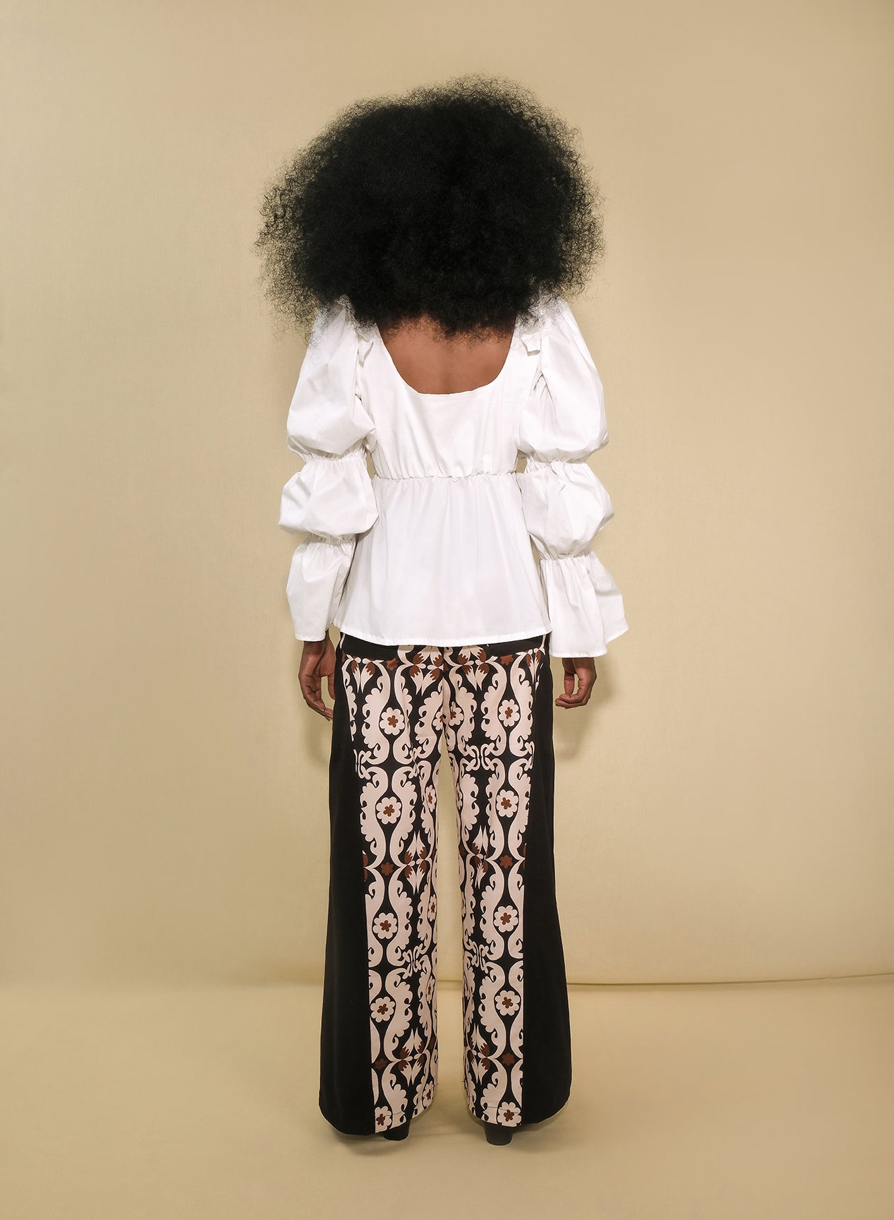 Model wearing white puff-sleeve poplin top with tie-front keyhole