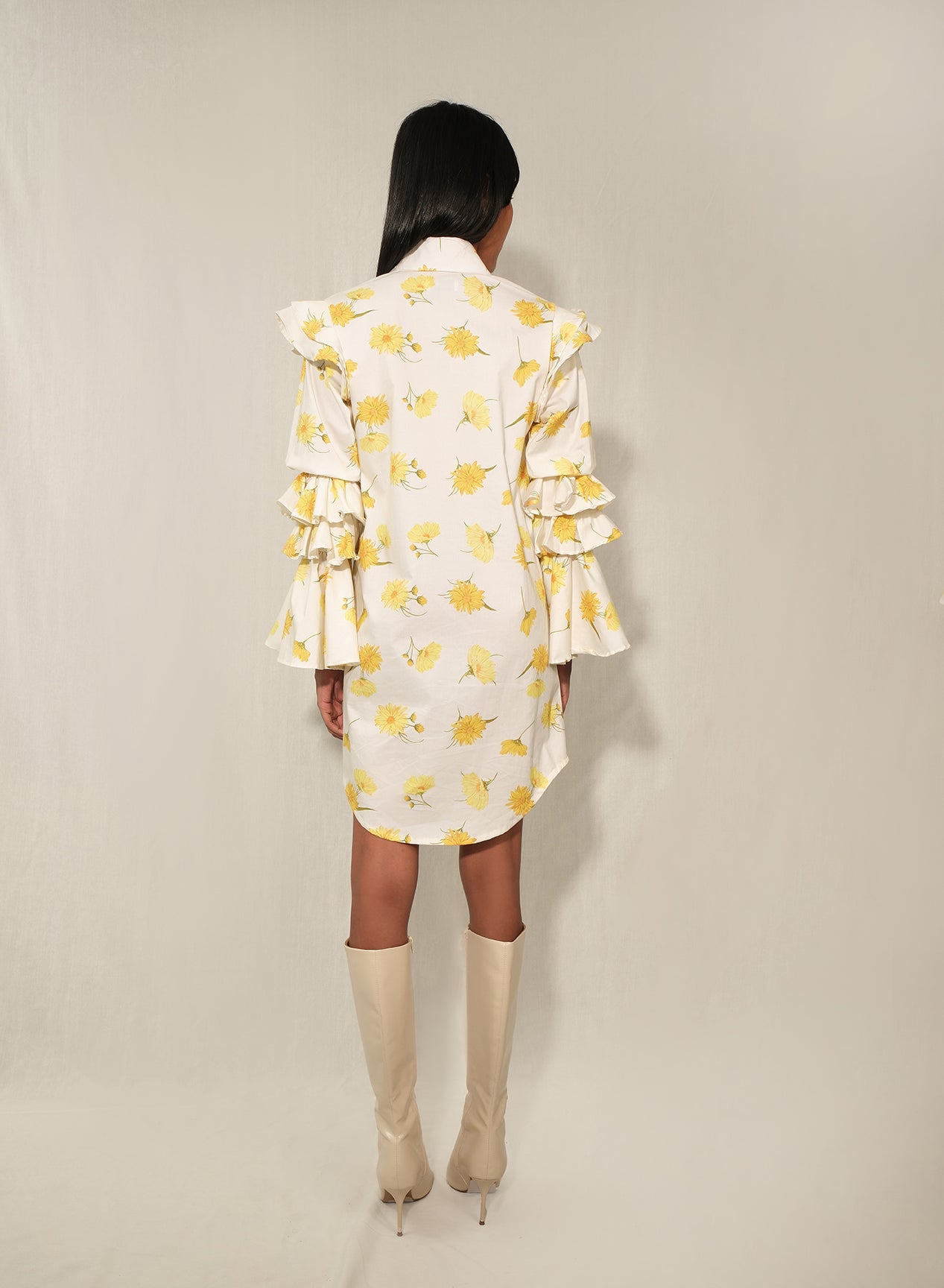 Model in ruffle-sleeve floral shirt dress in yellow daisy print, mini length.