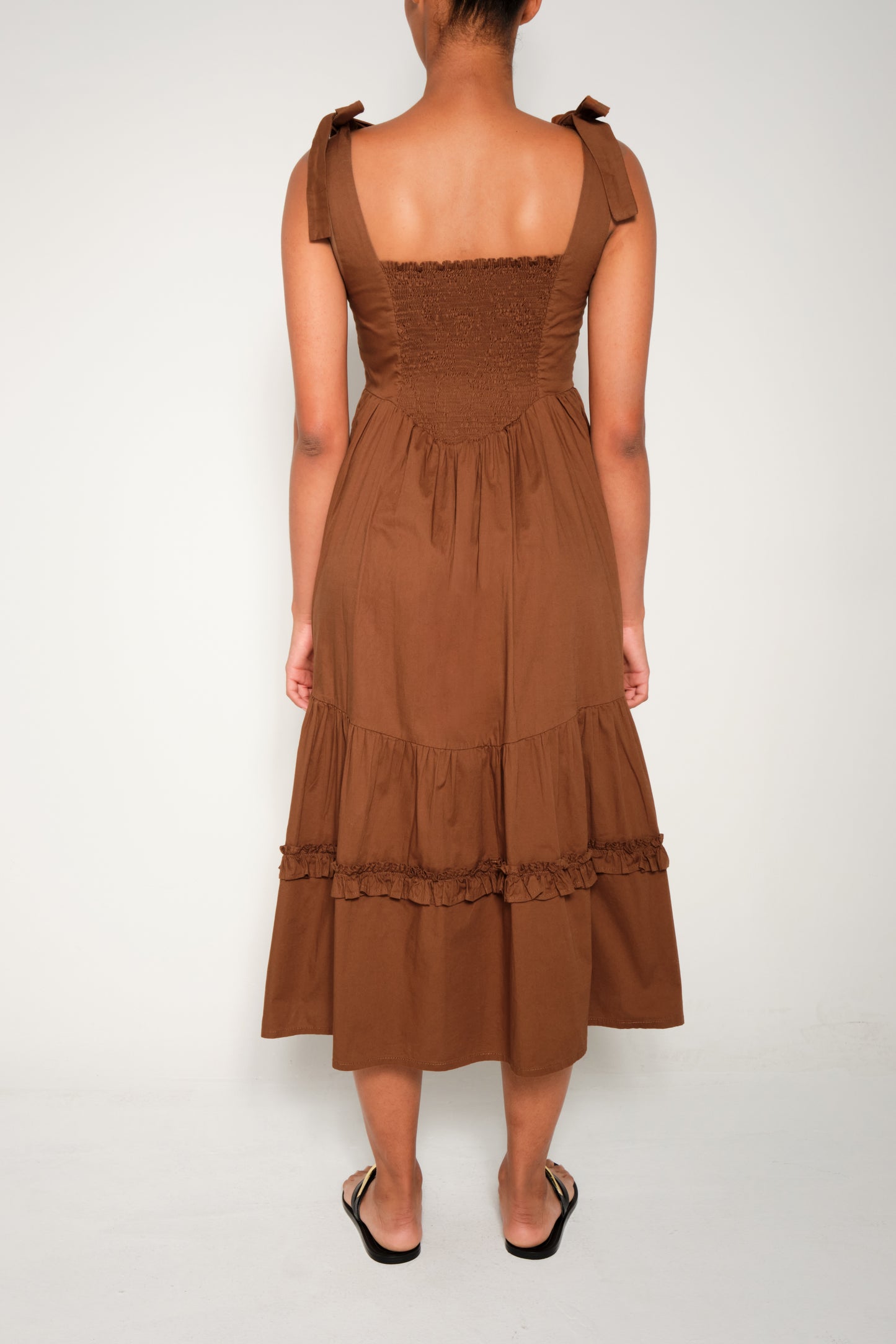 Model in fit-and-flare poplin midi dress with corset bodice, adjustable ties, and tiered ruffle skirt.