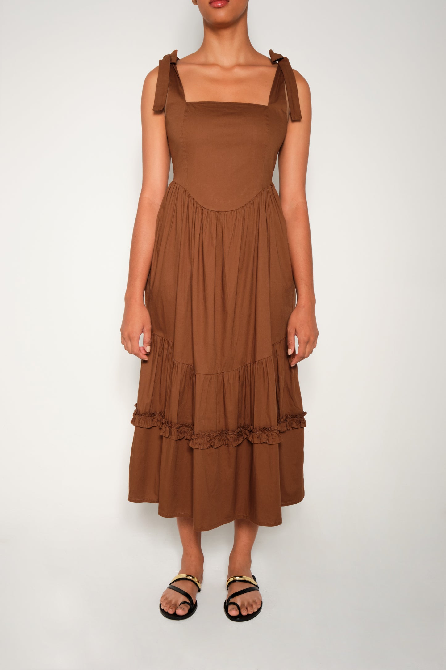 Model in fit-and-flare poplin midi dress with corset bodice, adjustable ties, and tiered ruffle skirt.