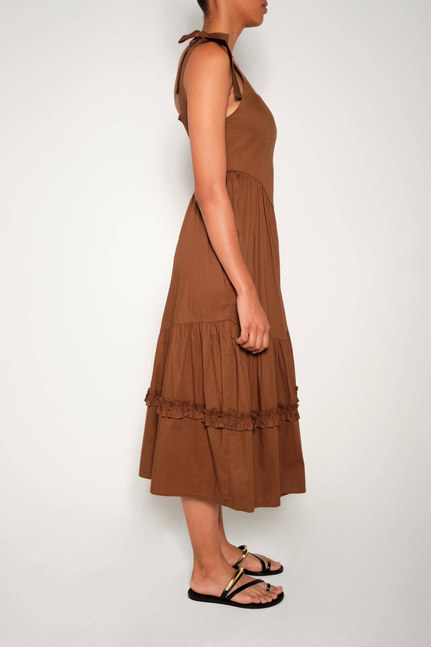 Model in fit-and-flare poplin midi dress with corset bodice, adjustable ties, and tiered ruffle skirt.
