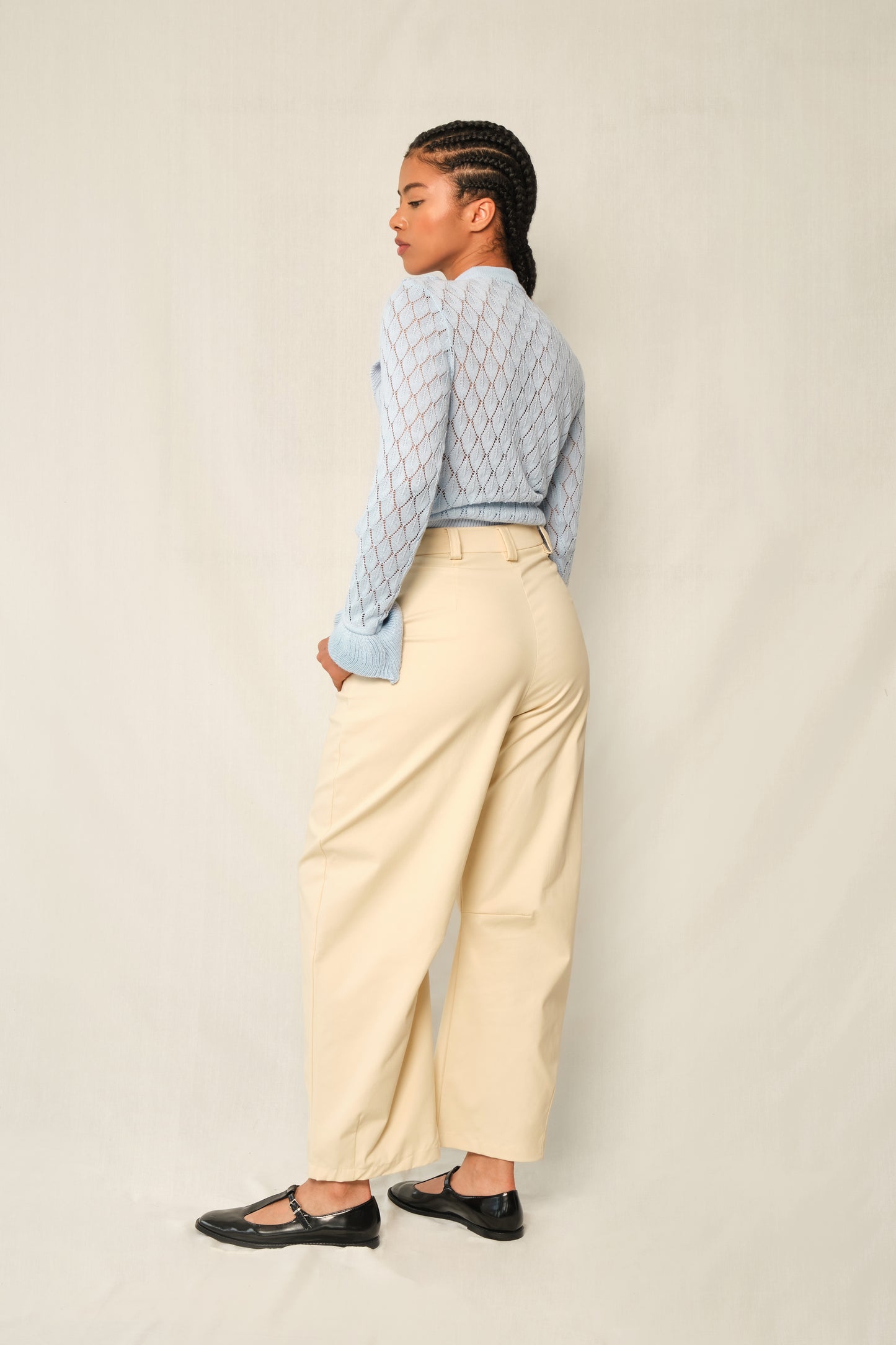 Light-blue pointelle knit sweater with V-ruffle and layered cuffs.