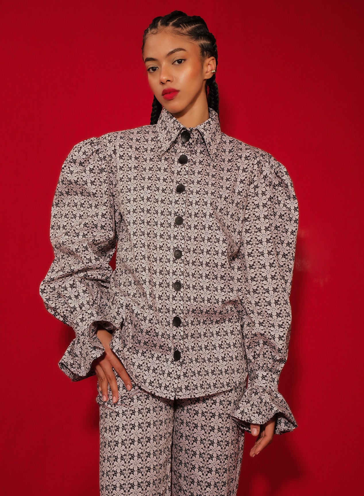 Model in macramé print poplin shirt with puff sleeves and flared ruffle cuffs.