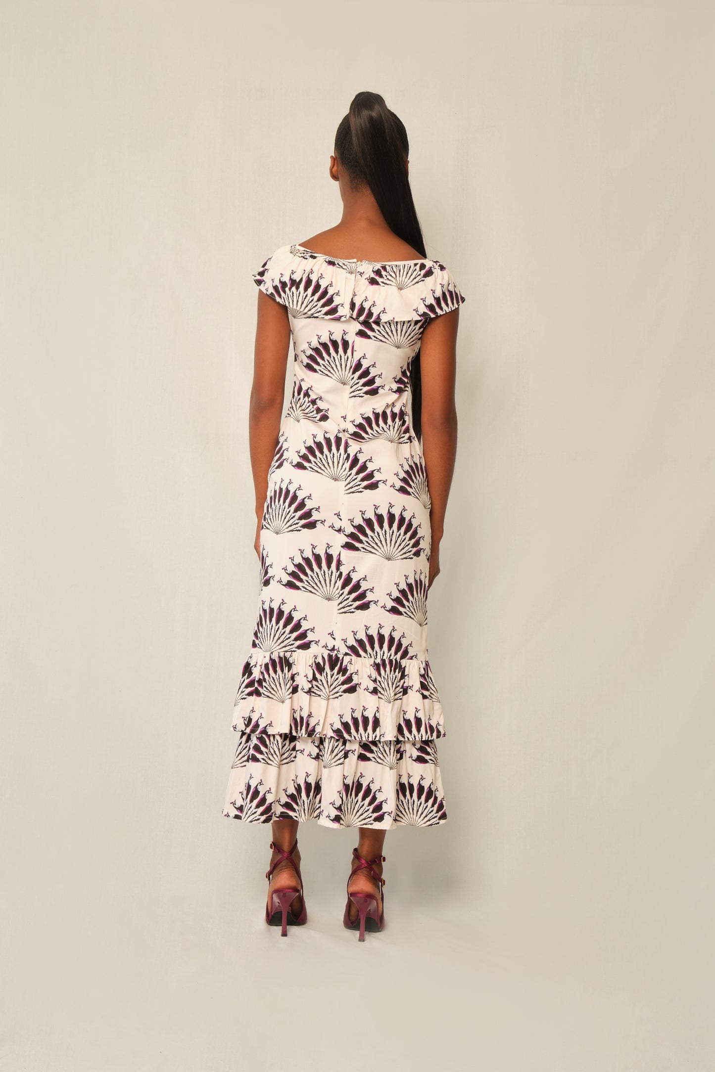 Model wearing fitted viscose midi dress in Throated Ivory print with ruffle neckline, tie keyhole, and double-tier flounce hem