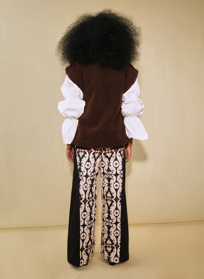 Model wearing brown faux-shearling vest with open front.
