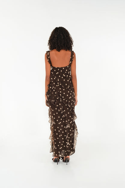 Woman wearing a black dress with gold polka dots on a white background