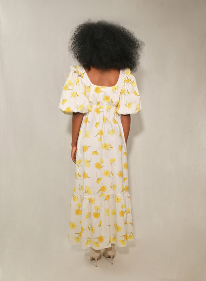 Model in floral puff-sleeve bow-front maxi dress with tiered skirt in yellow daisy print.