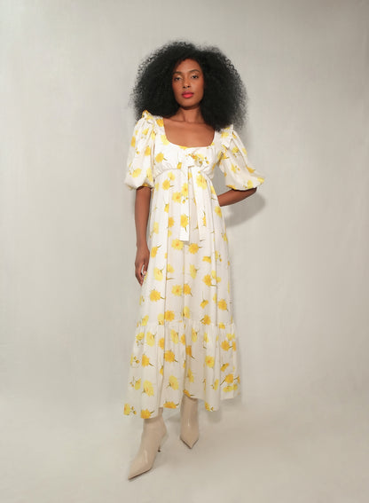 Model in floral puff-sleeve bow-front maxi dress with tiered skirt in yellow daisy print.