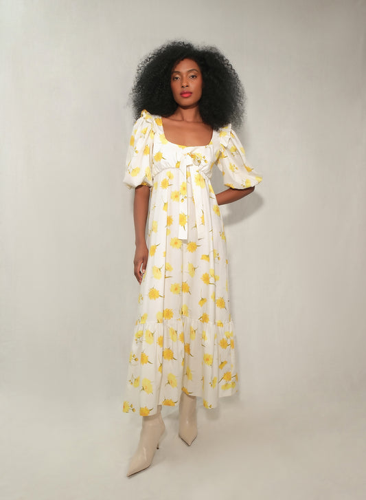 Model in floral puff-sleeve bow-front maxi dress with tiered skirt in yellow daisy print.