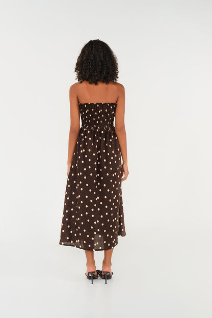 Woman wearing a strapless polka dot dress on a white background