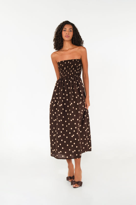 Woman wearing a strapless brown dress with white polka dots on a white background