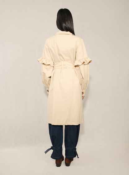 Model wearing women’s ruffle trench coat with belt and volant details