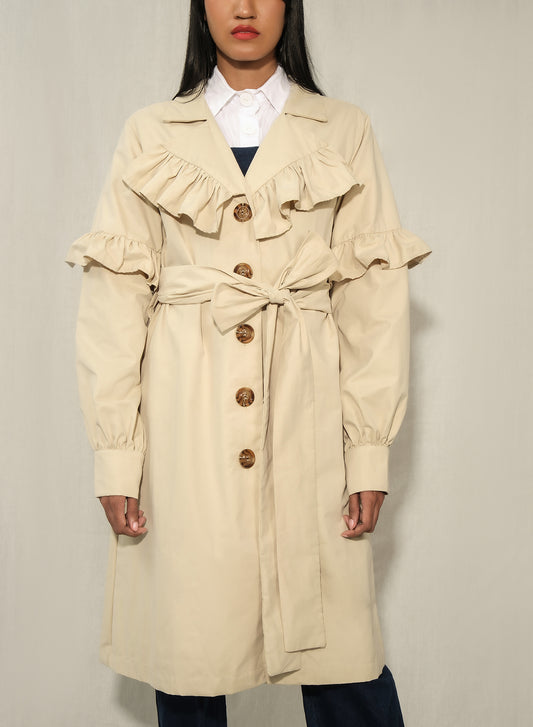 Model wearing women’s ruffle trench coat with belt and volant details