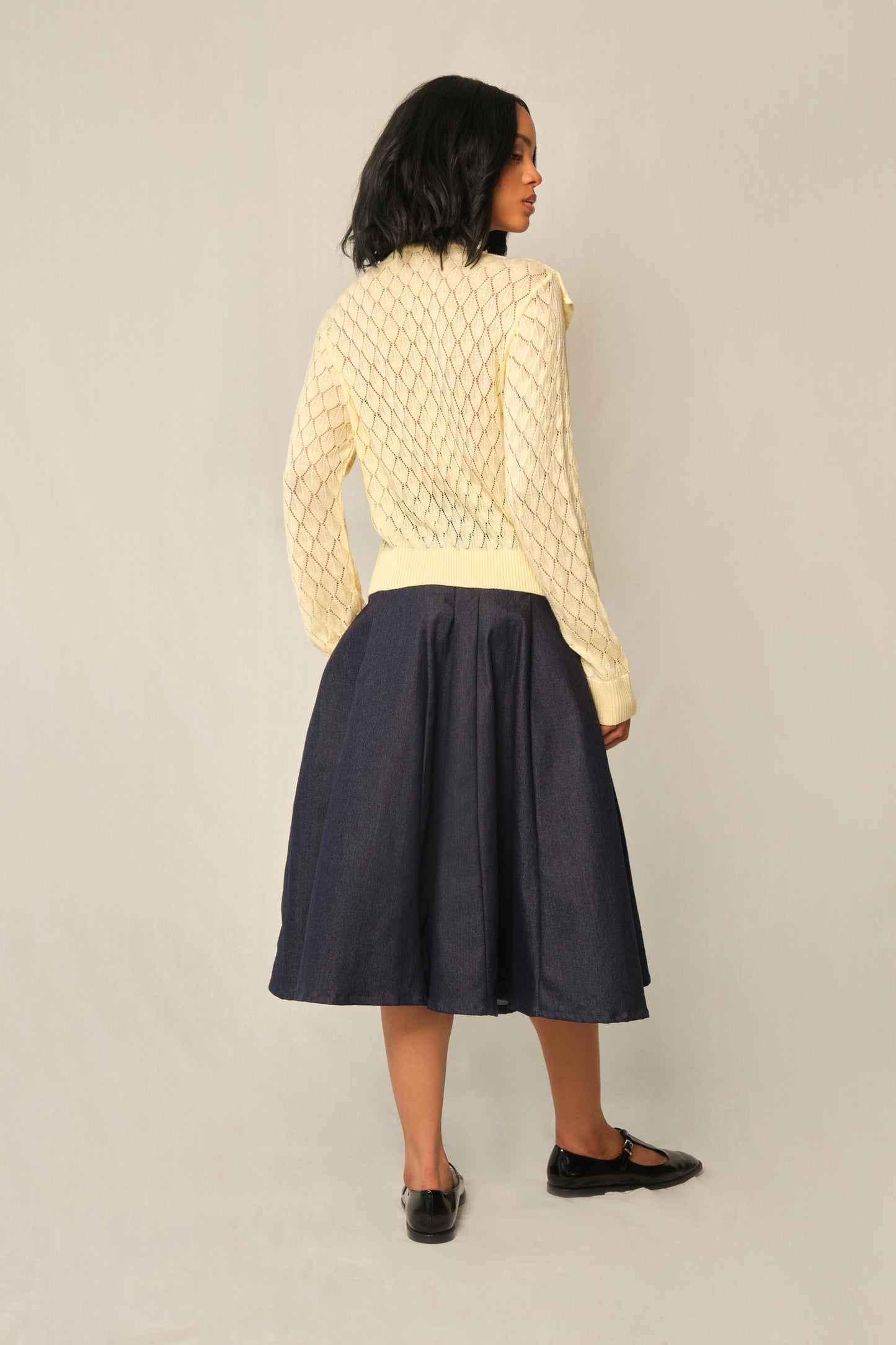 Model wearing indigo A-line denim panel midi skirt with vertical topstitch seams.