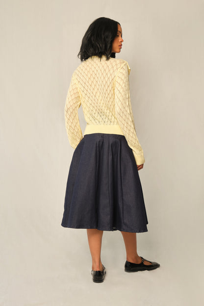 Model wearing indigo A-line denim panel midi skirt with vertical topstitch seams.