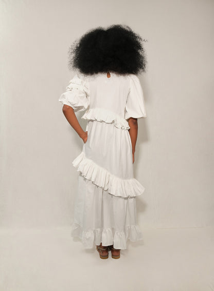 Model wearing white ruffle tiered poplin dress with puff sleeves and asymmetrical skirt.
