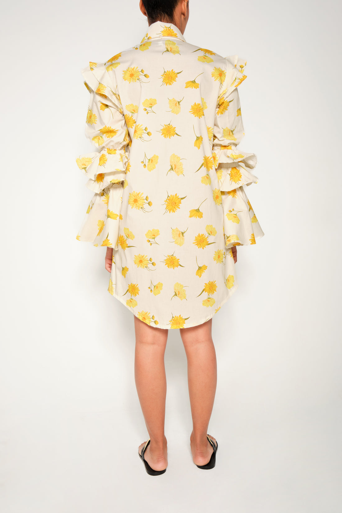 Model in ruffle-sleeve floral shirt dress in yellow daisy print, mini length.