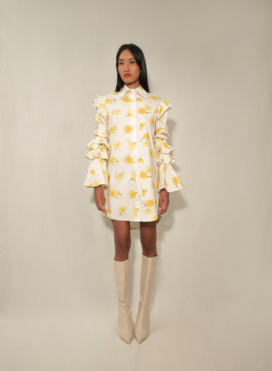 Model in ruffle-sleeve floral shirt dress in yellow daisy print, mini length.