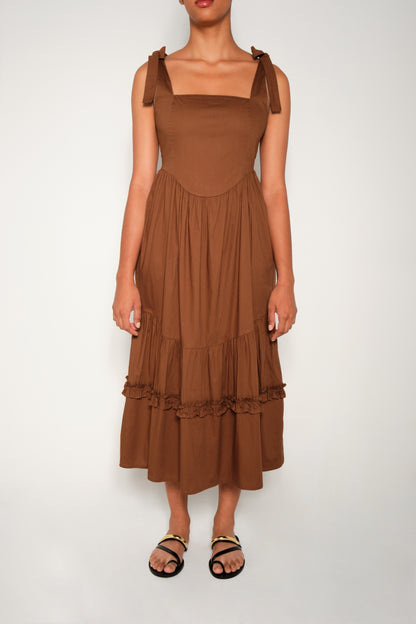Model in fit-and-flare poplin midi dress with corset bodice, adjustable ties, and tiered ruffle skirt.