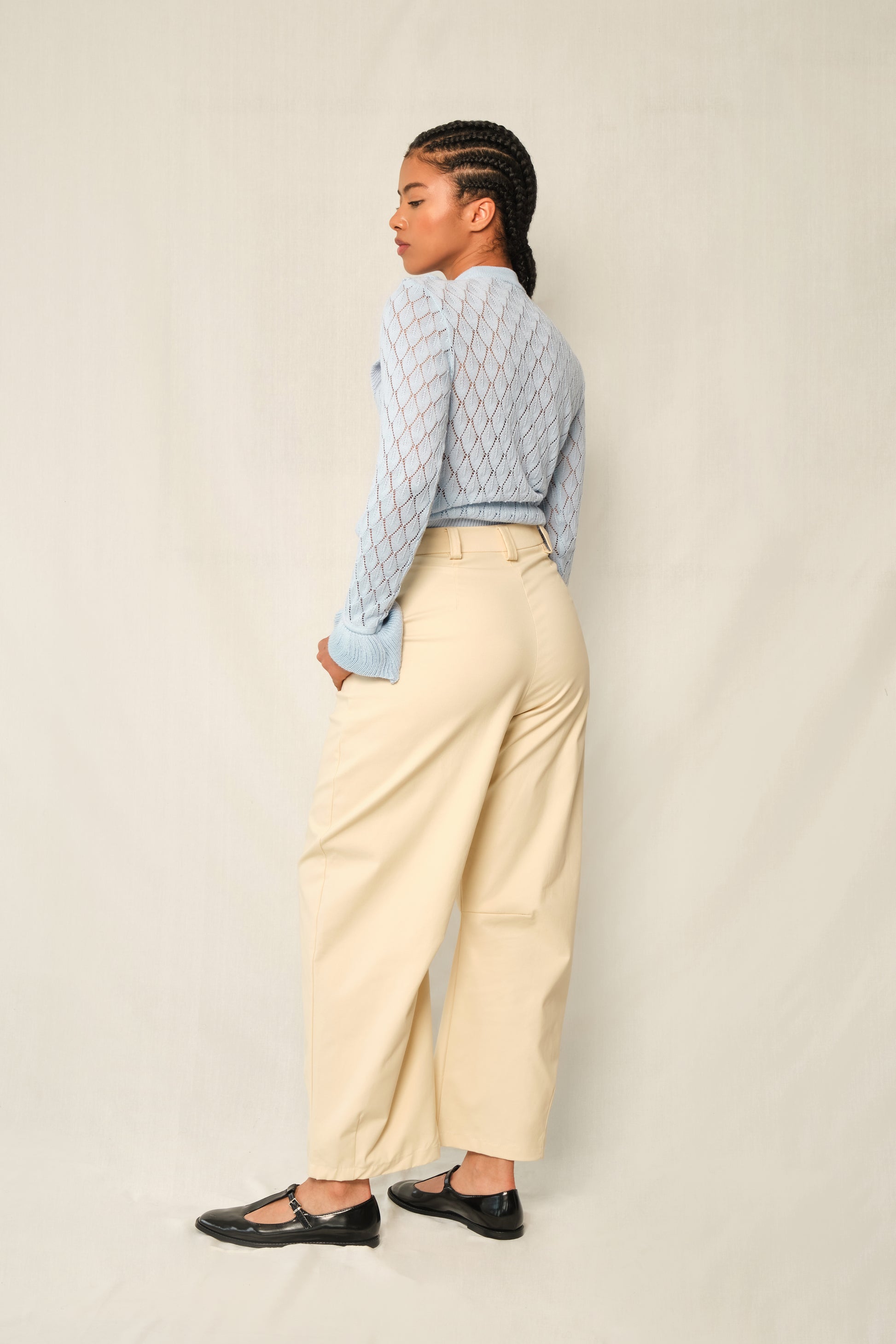 Light-blue pointelle knit sweater with V-ruffle and layered cuffs.