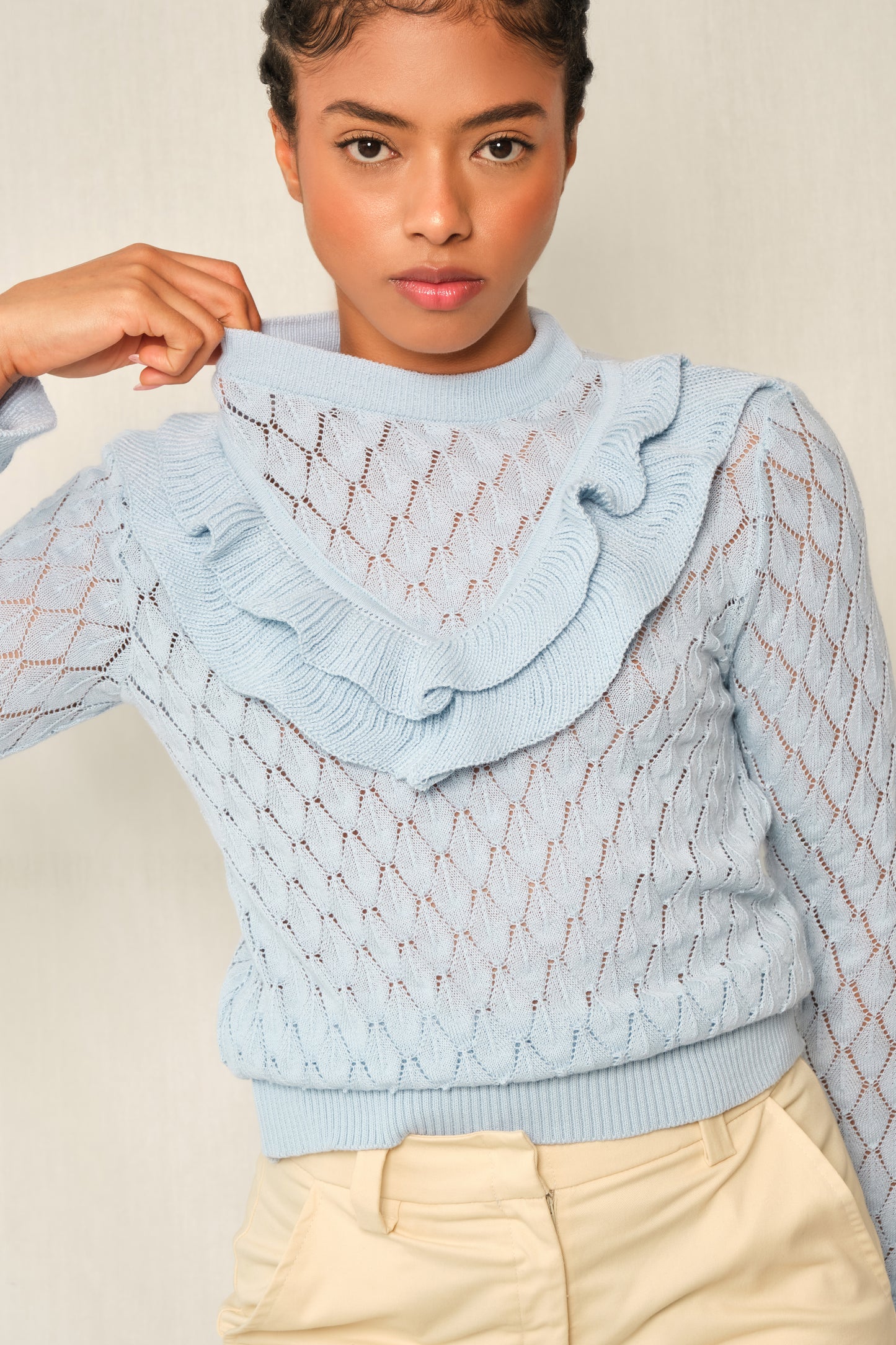Light-blue pointelle knit sweater with V-ruffle and layered cuffs.