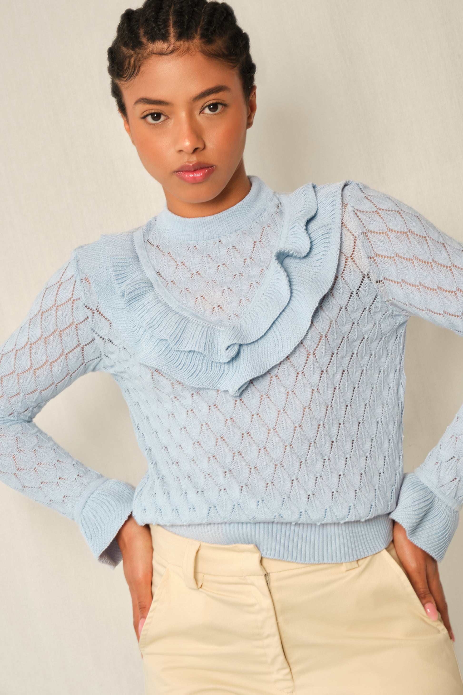 Light-blue pointelle knit sweater with V-ruffle and layered cuffs.