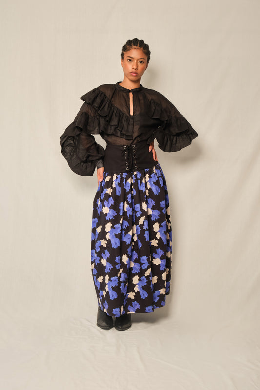Model wearing high-waisted lace-up corset maxi skirt with black yoke and Jacaranda print gathered skirt.