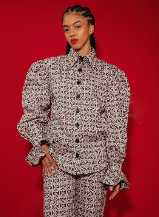 Model in macramé print poplin shirt with puff sleeves and flared ruffle cuffs.