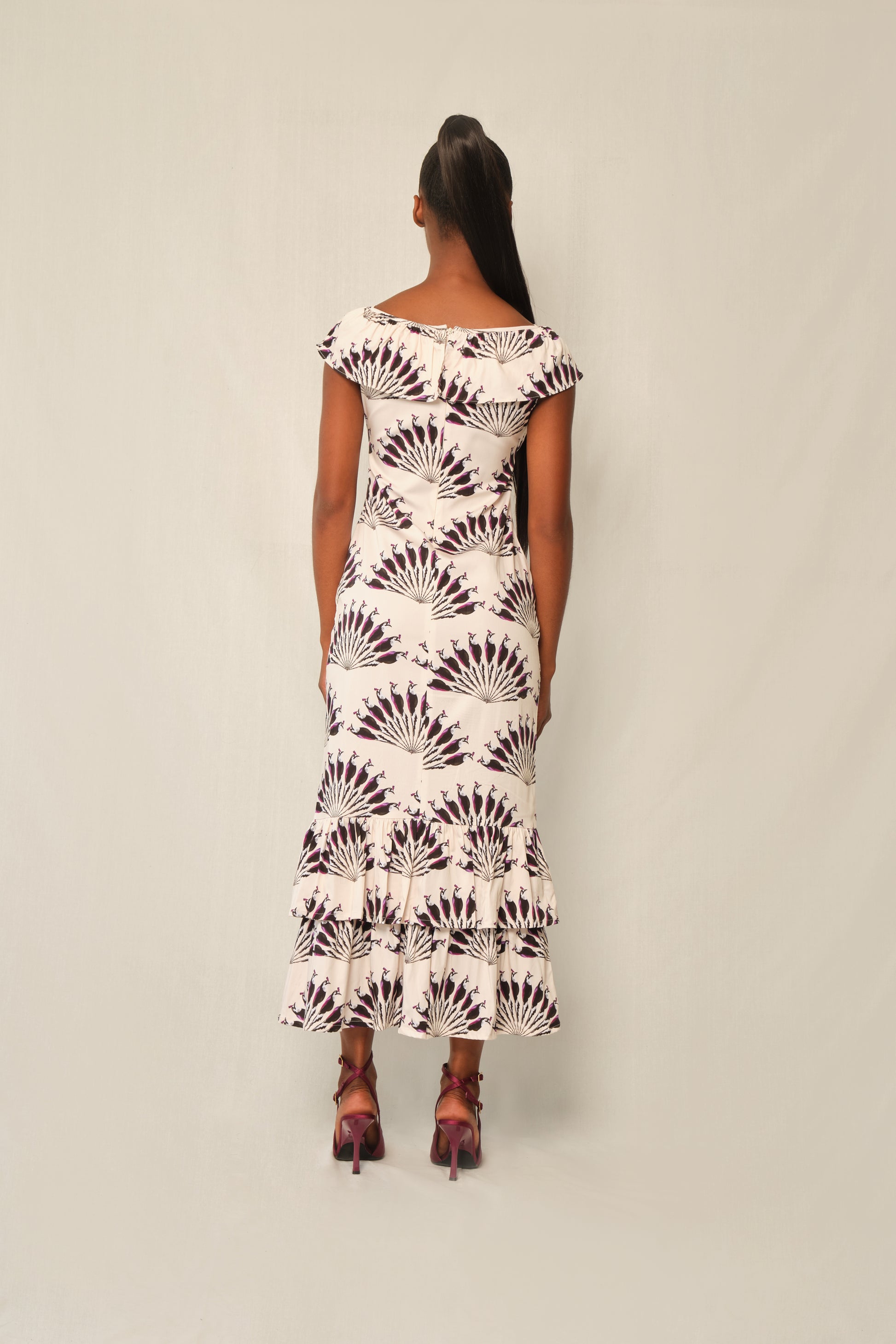Model wearing fitted viscose midi dress in Throated Ivory print with ruffle neckline, tie keyhole, and double-tier flounce hem