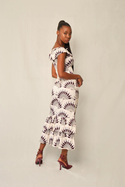 Model wearing fitted viscose midi dress in Throated Ivory print with ruffle neckline, tie keyhole, and double-tier flounce hem