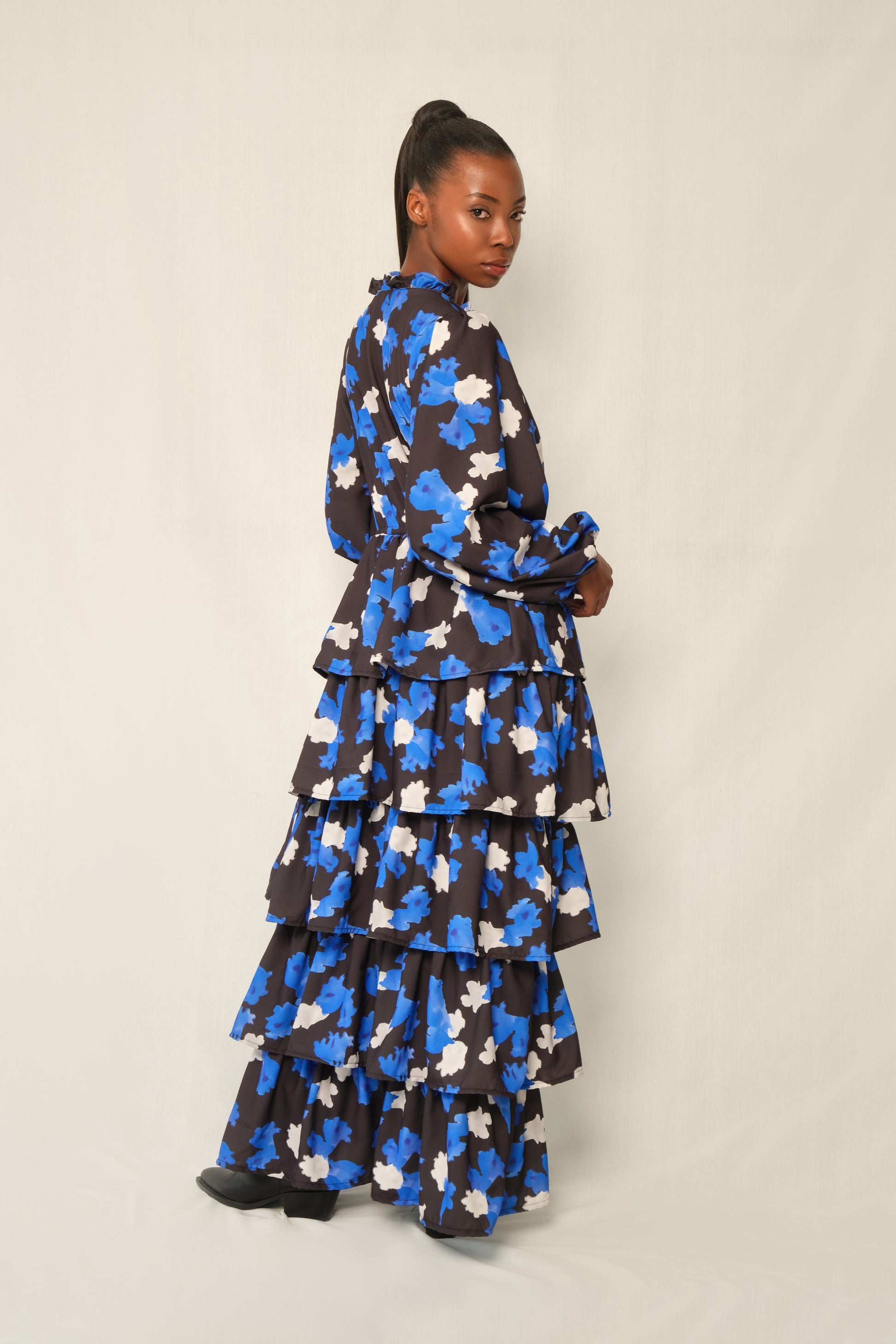 Model wearing tiered maxi dress in Jacaranda print with ruffled V-neckline and balloon sleeves, recycled crepe.