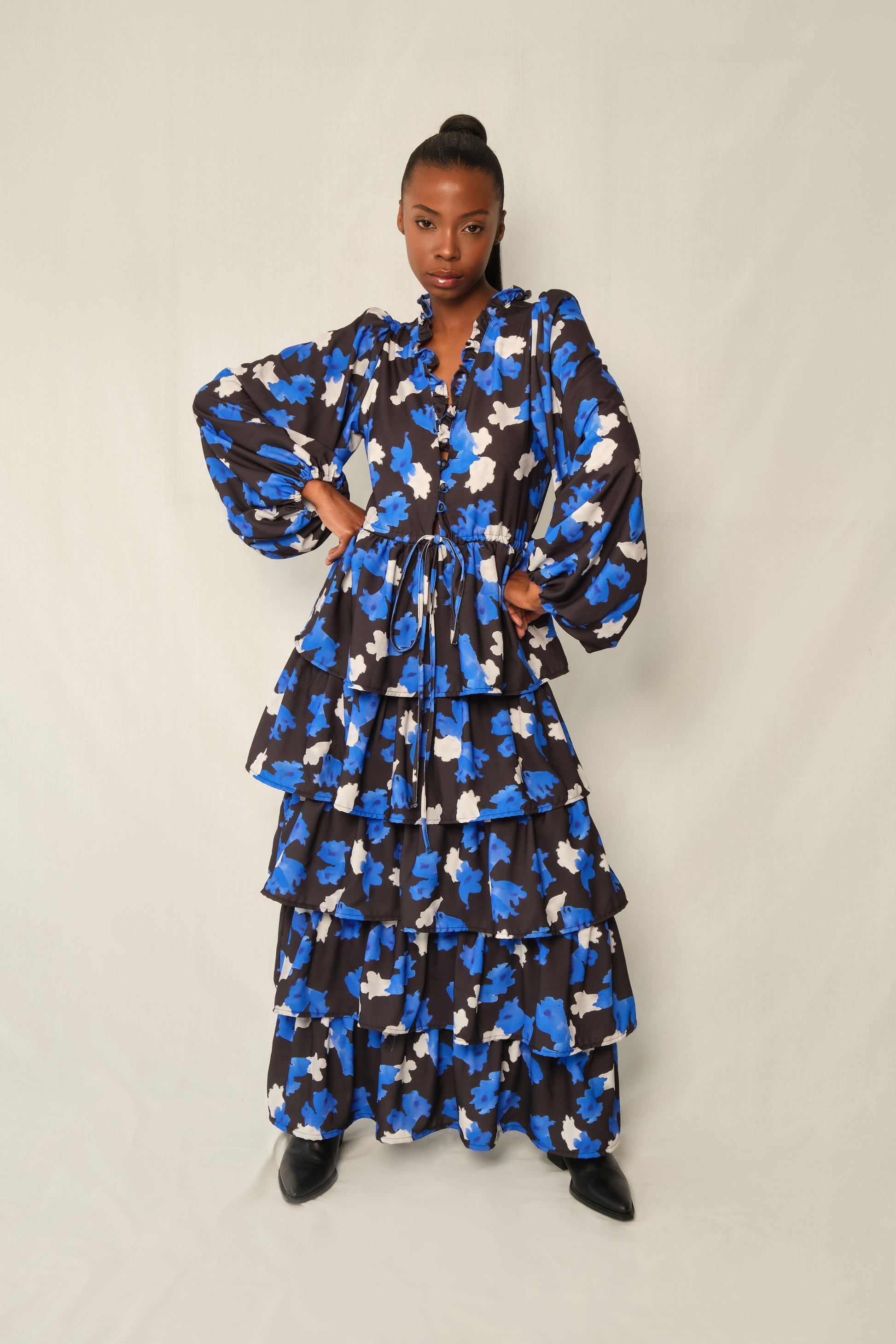 Model wearing tiered maxi dress in Jacaranda print with ruffled V-neckline and balloon sleeves, recycled crepe.