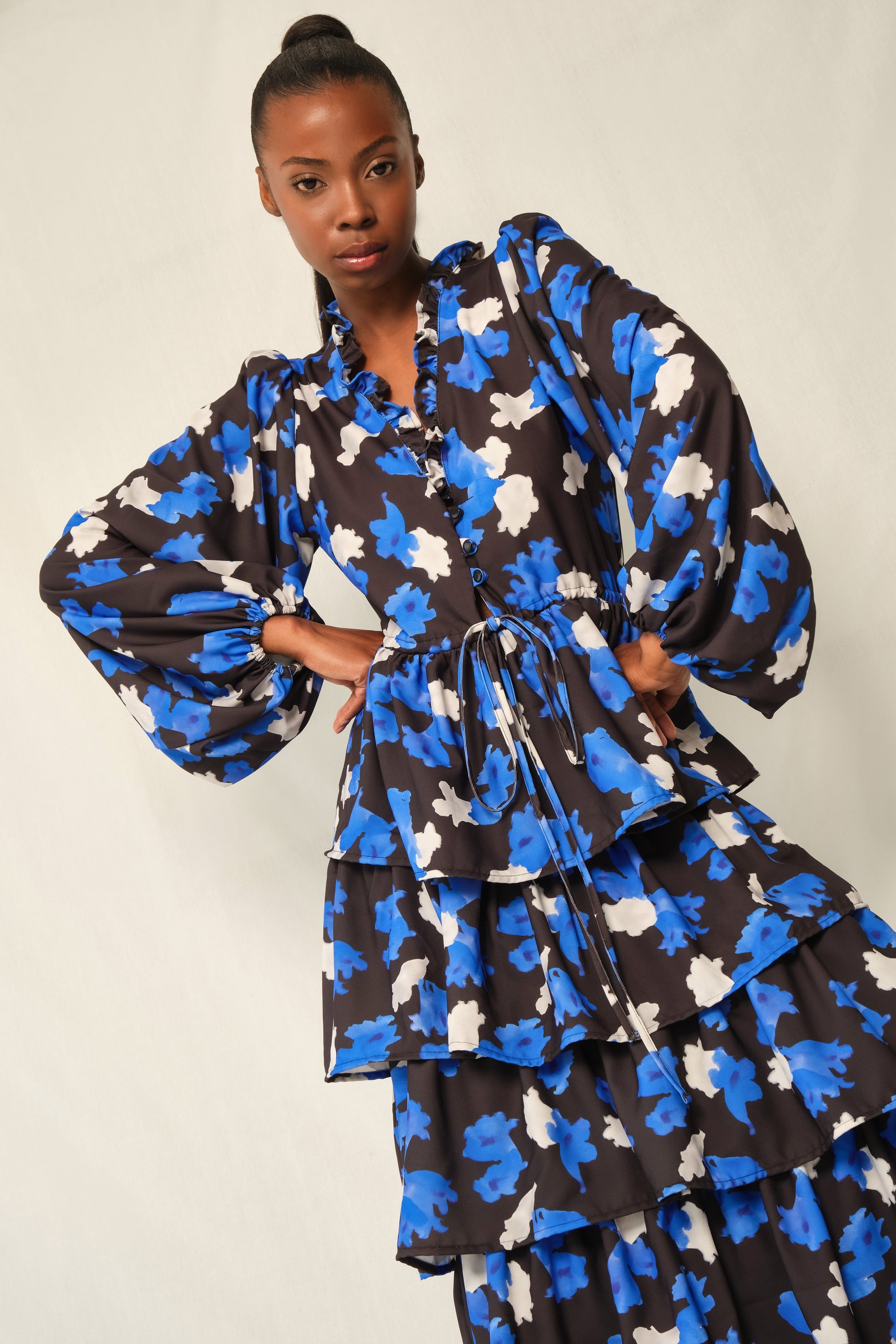 Model wearing tiered maxi dress in Jacaranda print with ruffled V-neckline and balloon sleeves, recycled crepe.