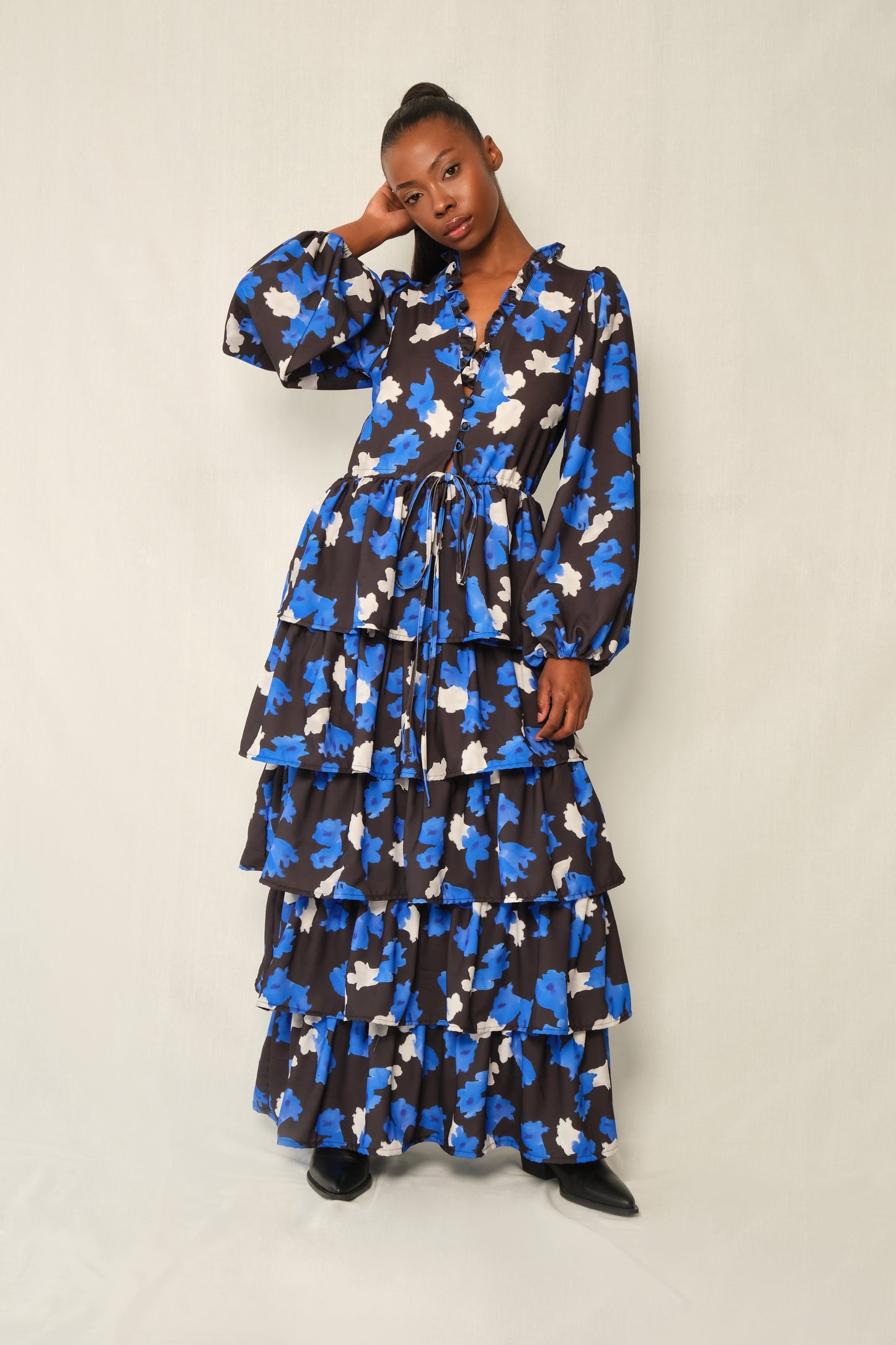 Model wearing tiered maxi dress in Jacaranda print with ruffled V-neckline and balloon sleeves, recycled crepe.