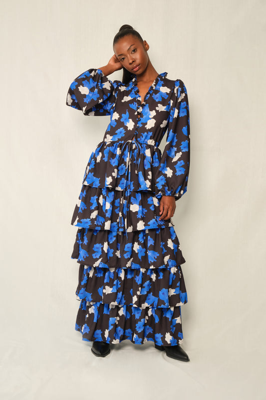 Model wearing tiered maxi dress in Jacaranda print with ruffled V-neckline and balloon sleeves, recycled crepe.